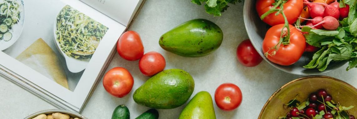 An appetizing display of fresh fruits and vegetables with a cookbook, perfect for healthy recipes.